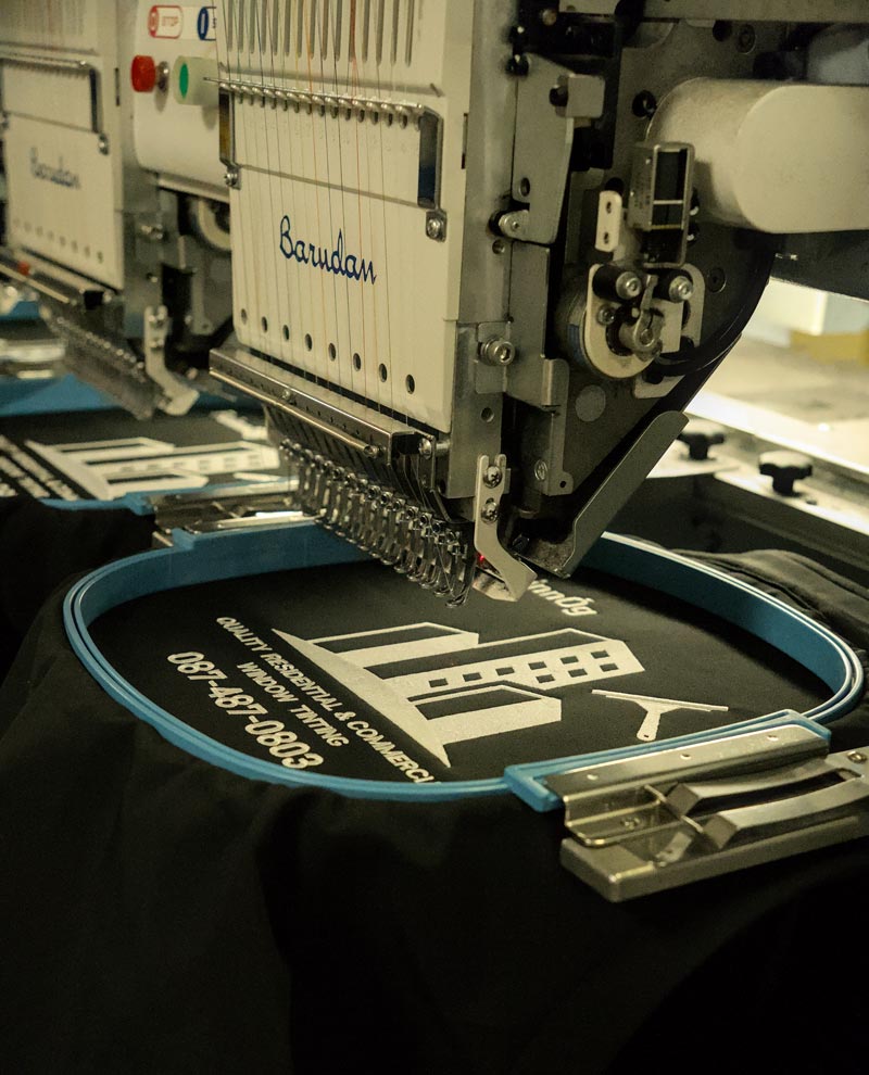Close-up of a custom logo being embroidered onto black fabric